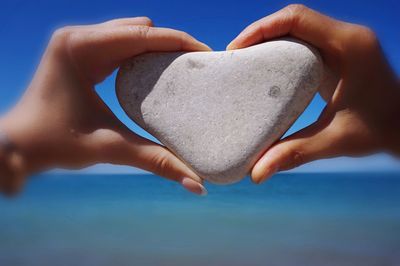 Close-up of hand holding heart shape on beach