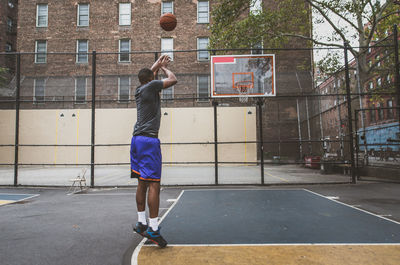 Young man practicing basketball in court