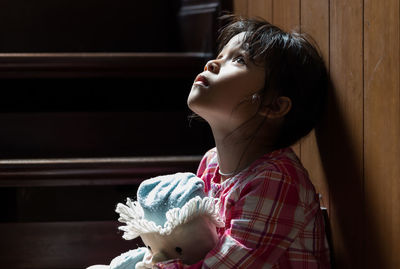 Cute girl with toy sitting on steps at home