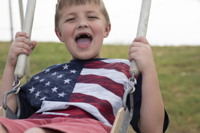 Portrait of happy boy sitting on swing