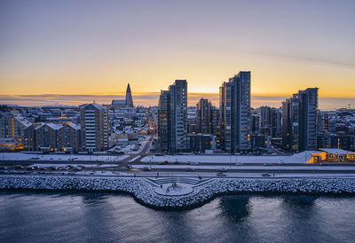 Snowy city and embankment during sunset