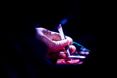 Cropped hand holding tweezers in darkroom