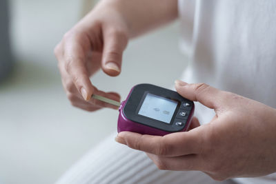 Hands of woman using digital glucometer at home
