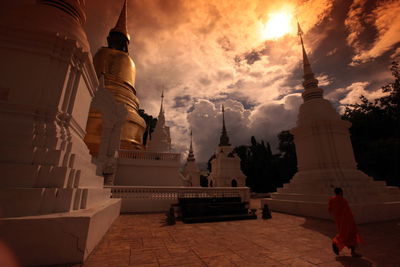 Full length of monk walking by wat suan dok against sky during sunset