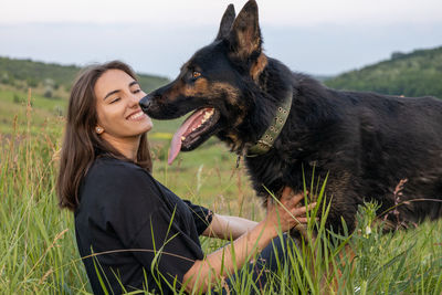 Portrait of young woman with dog on grassy field