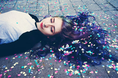 High angle view of woman lying with colorful confetti on footpath