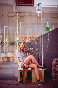 Portrait of woman sitting on seat in city