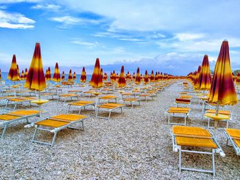 Panoramic view of empty chairs at beach against sky