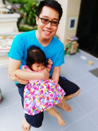 High angle view of father holding cute daughter while sitting outdoors