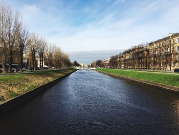 Canal amidst bare trees against sky