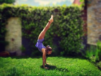 Tilt-shift image of girl doing handstand in park