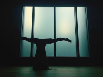 Silhouette woman exercising in gym by window