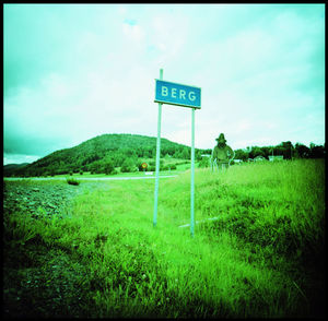 Road sign on field against sky