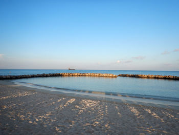 Scenic view of beach against clear blue sky