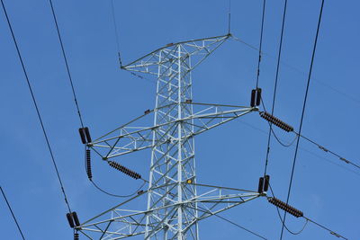 Low angle view of electricity pylon against blue sky