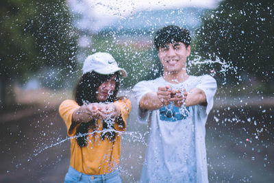 Portrait of smiling couple splashing water on road