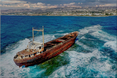 Shipwreck on reef with waves blue sky and clouds