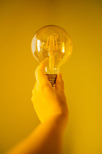 Person holding light bulb against yellow background