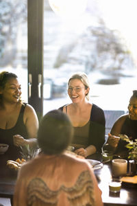 Happy female friends enjoying breakfast together at retreat center