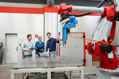 Colleagues examining robots in factory