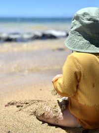 Midsection of woman wearing hat on beach