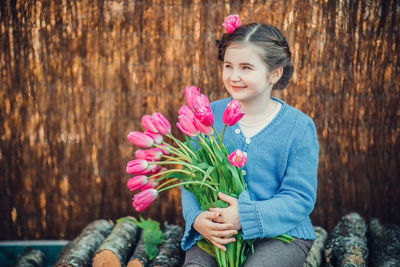 Low angle view of girl holding pink flower