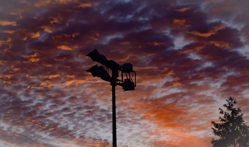 Low angle view of silhouette pole against orange sky