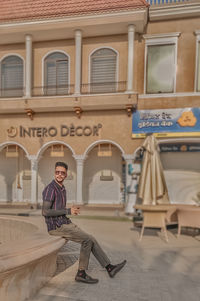 Portrait of man sitting in front of building