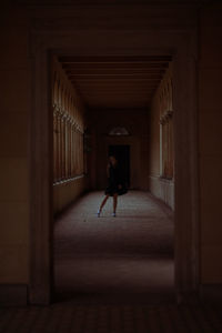 Full length of young woman standing in dark corridor