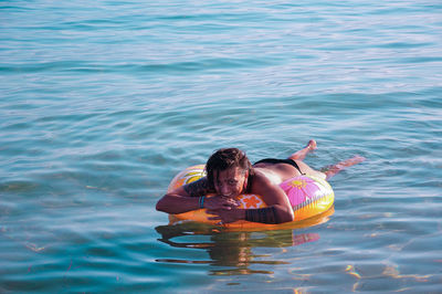 Portrait of mid adult woman with inflatable ring floating on sea