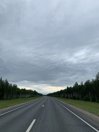 Empty road along trees and sky