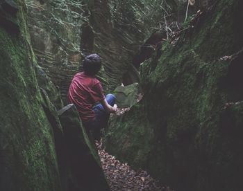 Rear view of person on rock in forest