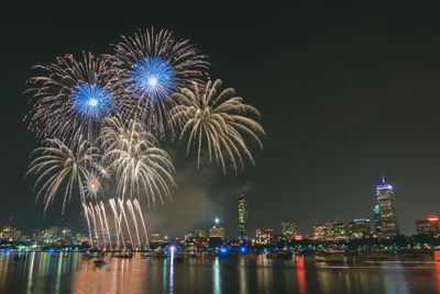 Firework display over illuminated buildings in city at night