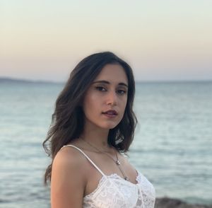 Portrait of young woman standing at beach during sunset