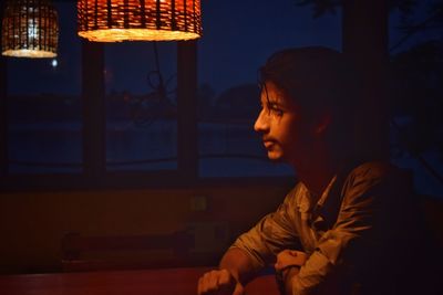 Man looking at illuminated lamp at home