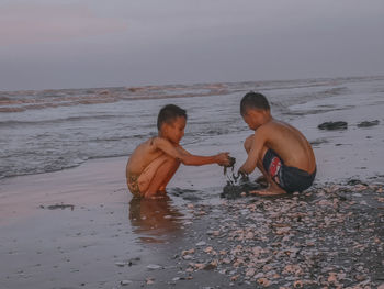 Full length of shirtless boy on beach against sky