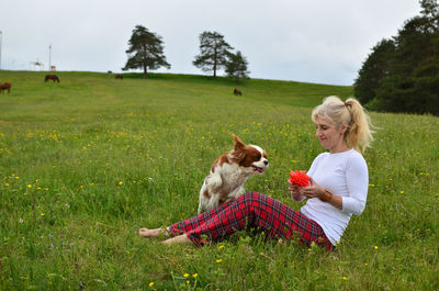 Cavalier king charles spaniel dog and woman playing in the countryside