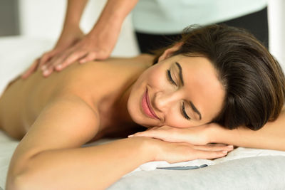 Midsection of masseuse giving massage to young woman relaxing at spa