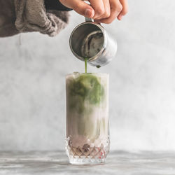 Midsection of person pouring drink in glass jar