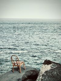 High angle view of empty chair on rock by sea