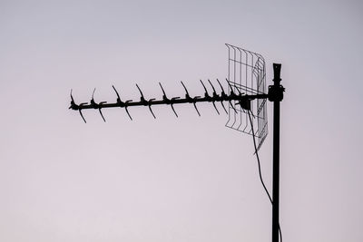 Low angle view of silhouette tv antenna against clear sky