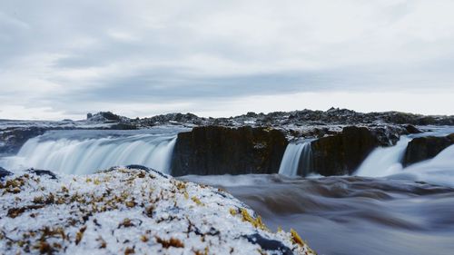 Scenic view of waterfall against sky