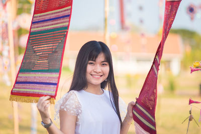 Portrait of smiling young woman standing by colorful decorations