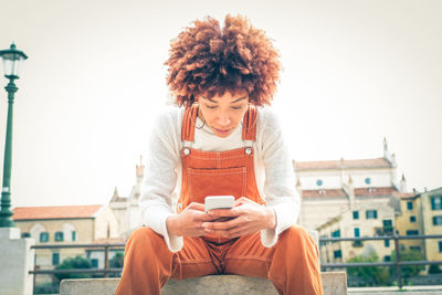 Low angle view of woman using mobile phone outdoors