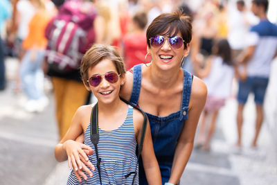 Smiling mother and son wearing sunglasses while standing in city