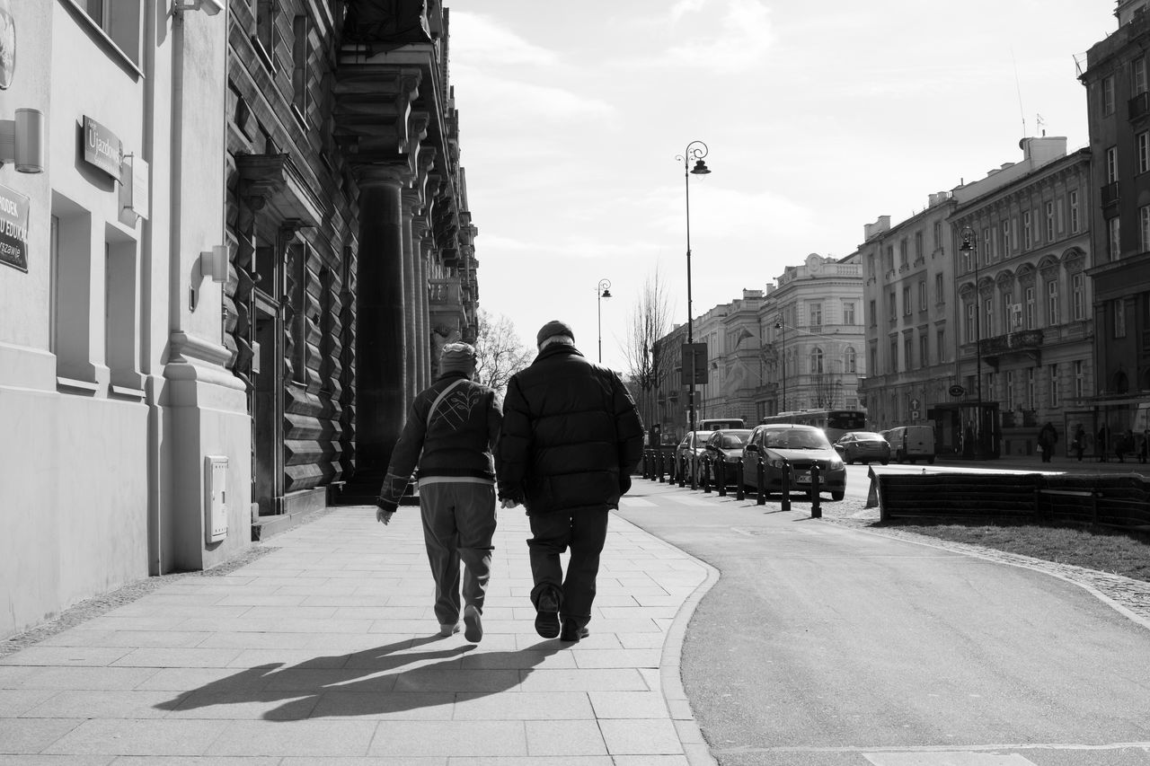 REAR VIEW OF PEOPLE WALKING ON STREET IN CITY