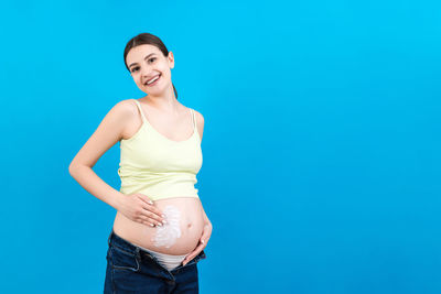 Portrait of a smiling young woman against blue background