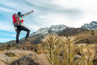 Rear view of man standing on rock against sky