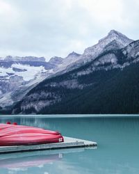 Kayaks by calm lake against mountains