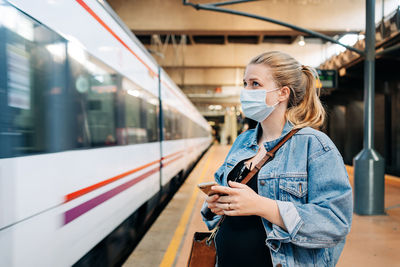 Full length of woman standing by train at railroad station